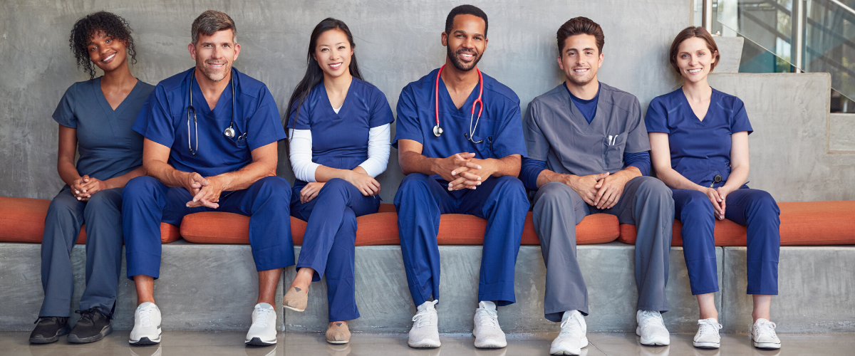 group-of-nurses-in-blue-scrubs-sitting-on-orange-bench
