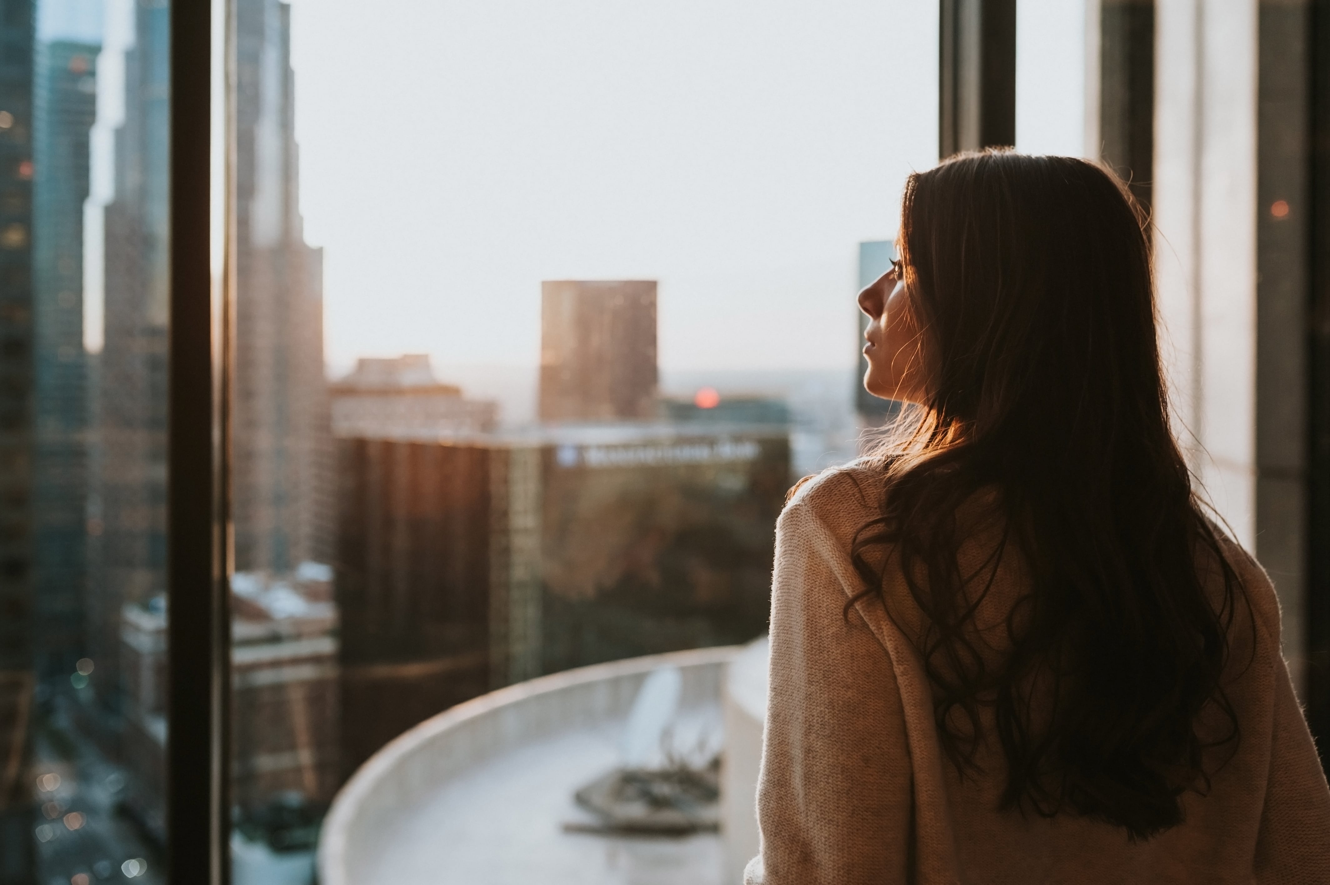 woman-staring-at-city-skyline-sunset-min